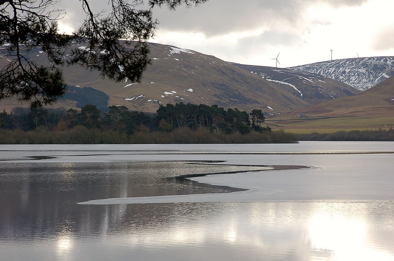 Thin ice on Gladhouse Reservoir Ice persisting in places during the cold spell of weather. The wind turbines are part of the Bowbeat windfarm.