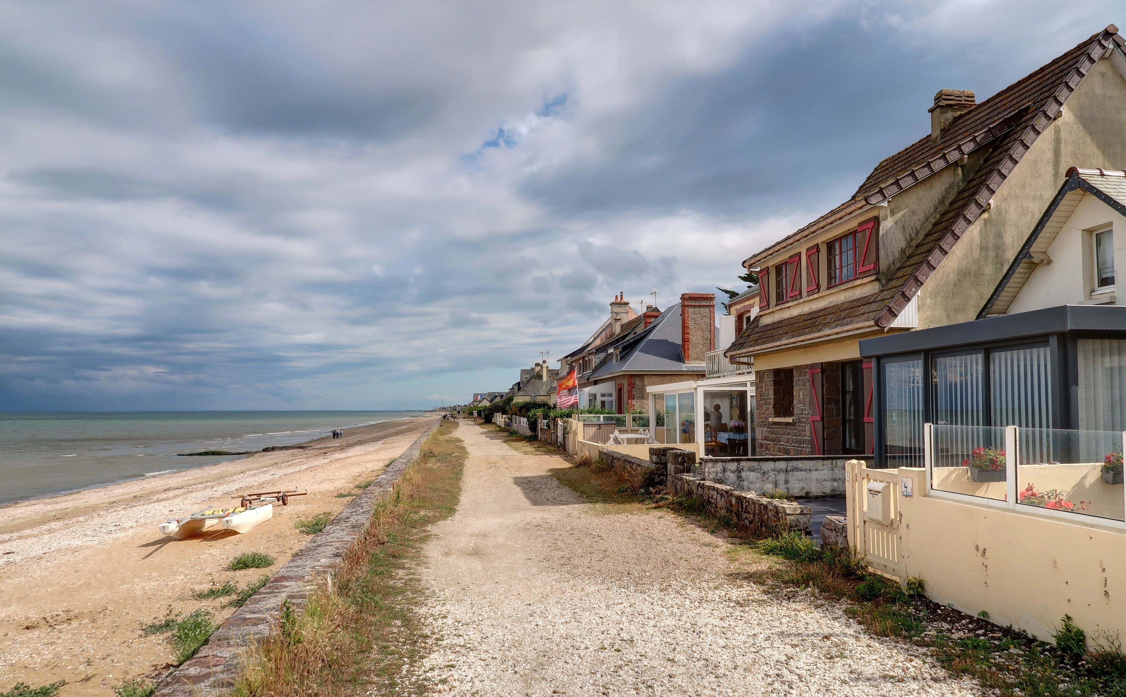 A coastal road with houses, a beach, and the sea.