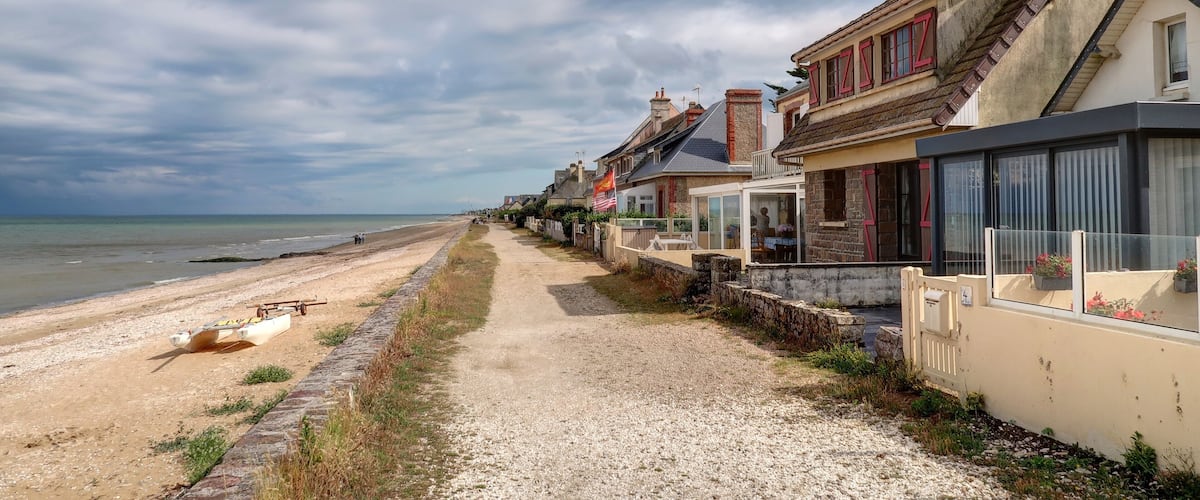 A coastal road with houses, a beach, and the sea.
