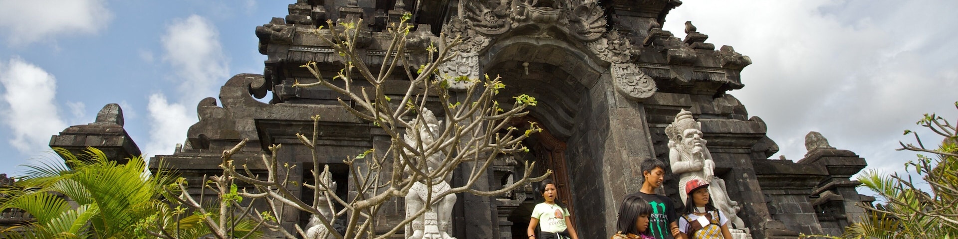 A temple entrance with intricate carvings and a stone bridge leading up to it.