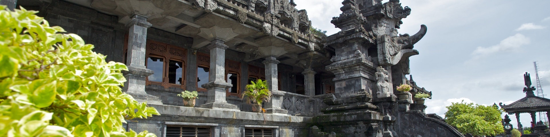 A traditional Balinese temple with intricate carvings, a central tower, and a surrounding pond with lotus flowers.