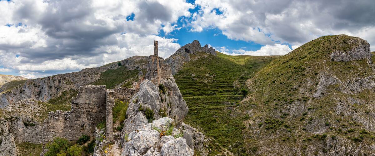 A mountainous landscape with ruins and terraced fields.