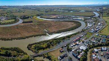 A river winding through a town with industrial buildings and a bridge.