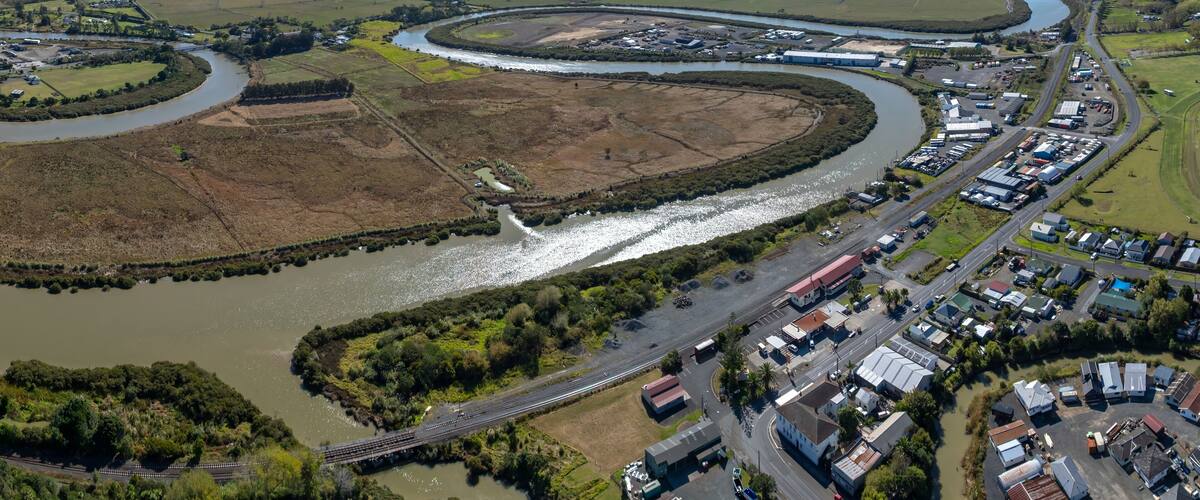 A river winding through a town with industrial buildings and a bridge.