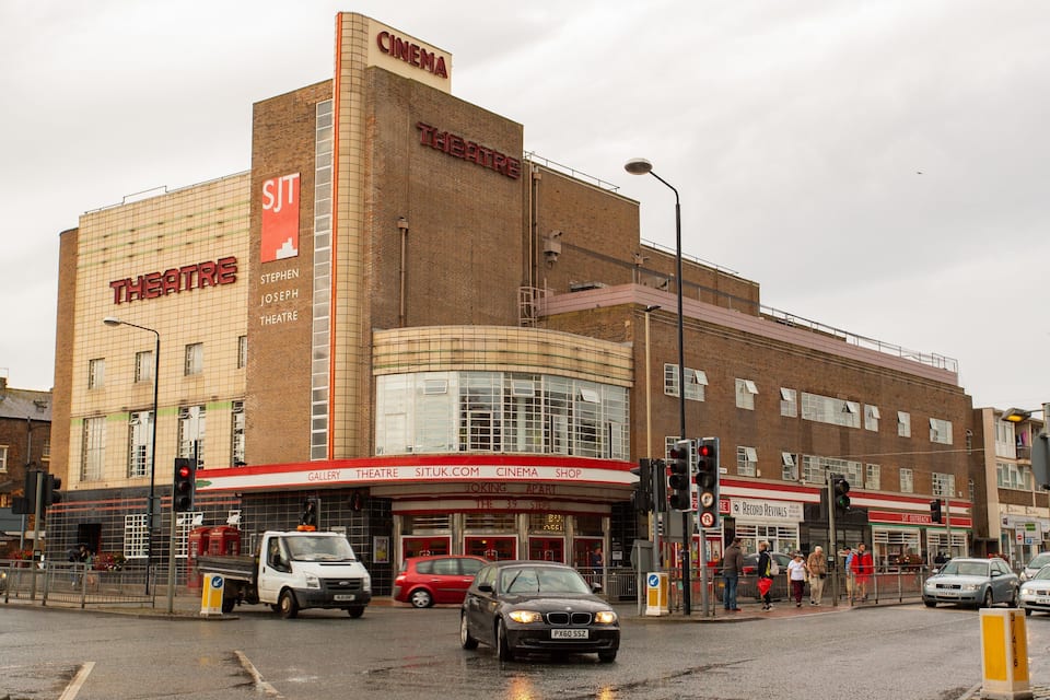 Un immeuble à plusieurs étages abritant une salle de cinéma et un théâtre au rez-de-chaussée.