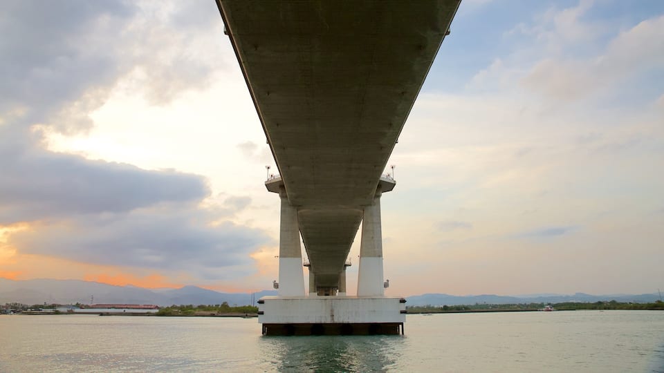A bridge over water with mountains in the background.