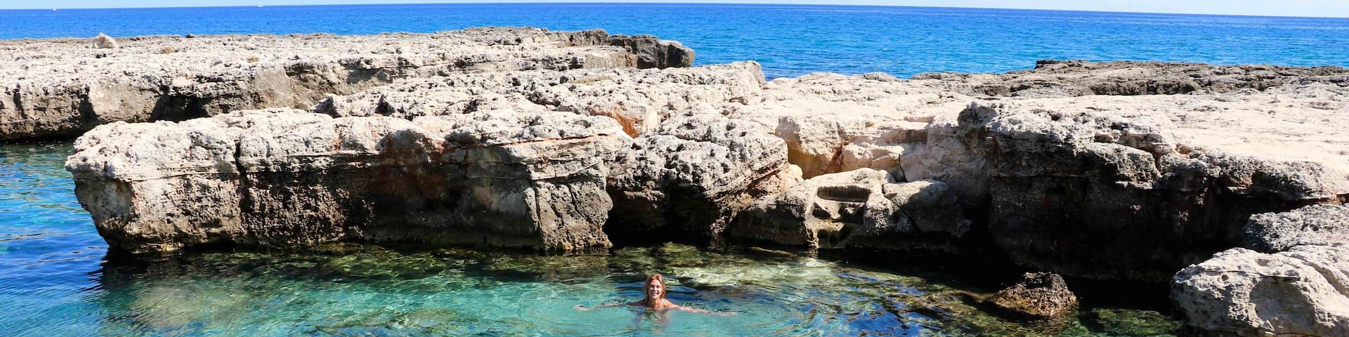 Água cristalina. Pedras claras contrastando com o azul do mar.