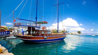 Um barco de madeira tradicional atracado em um iate clube, com água azul cristalina e céu ensolarado.