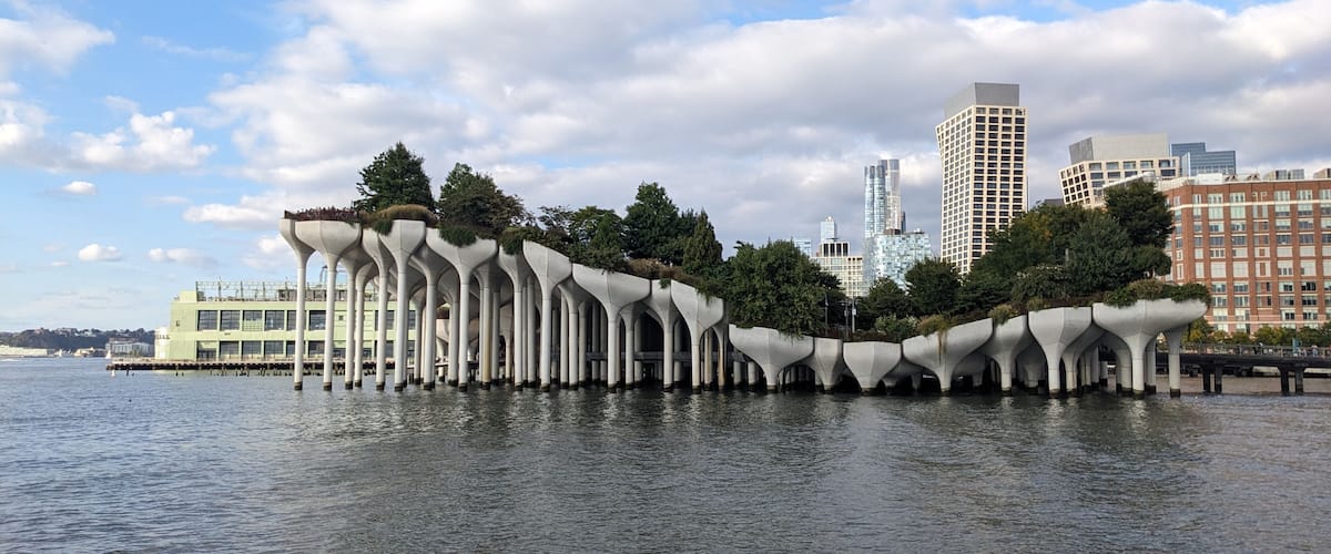 A waterfront with a unique architectural structure featuring multiple arches and greenery.