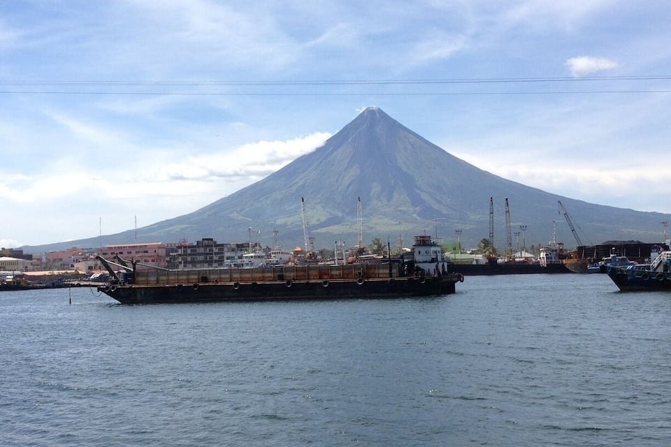 A cargo ship in a harbor with a mountain in the background.
