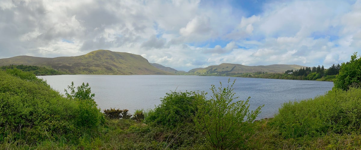 A lake surrounded by hills and greenery.