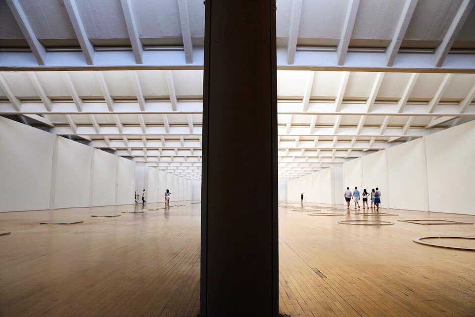 An interior space with a high ceiling, wooden floor, and white walls.