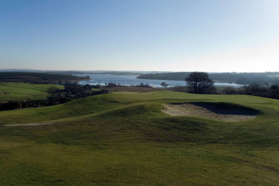 A golf course with a water body in the background.