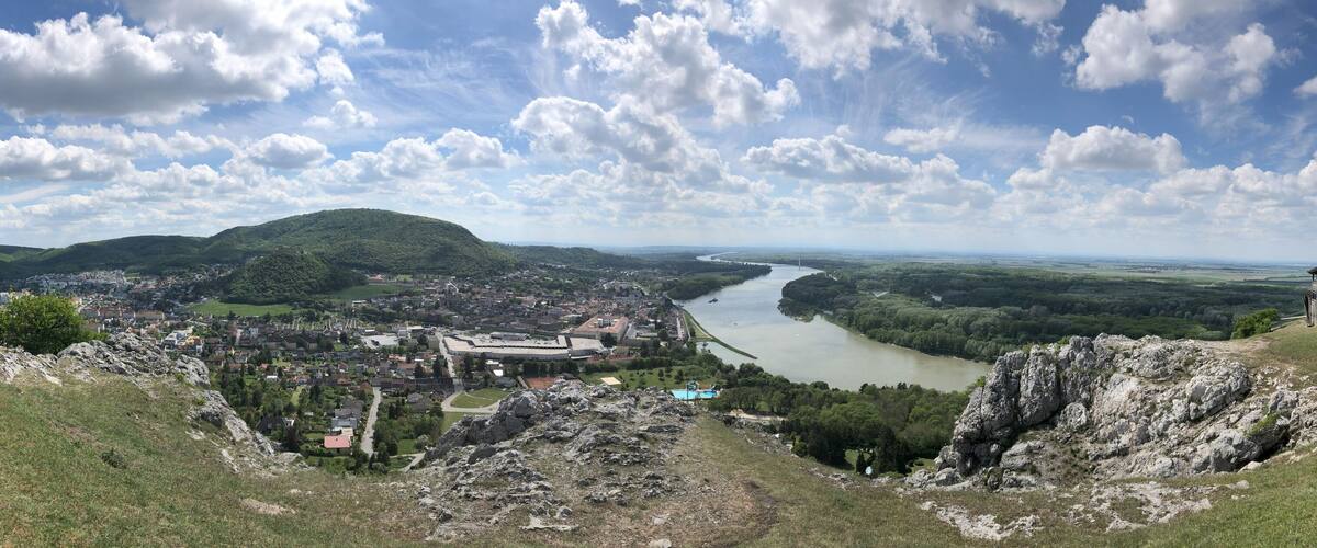 A river flowing through a valley with a town and a hill with a structure on top.