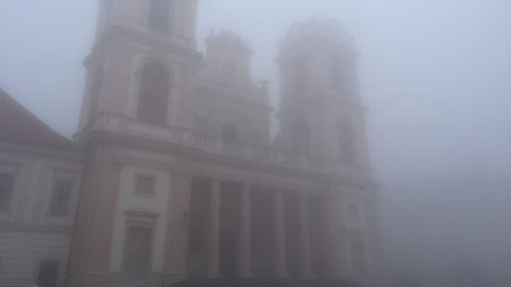 A foggy view of a historic building with a bell tower and classical architecture.