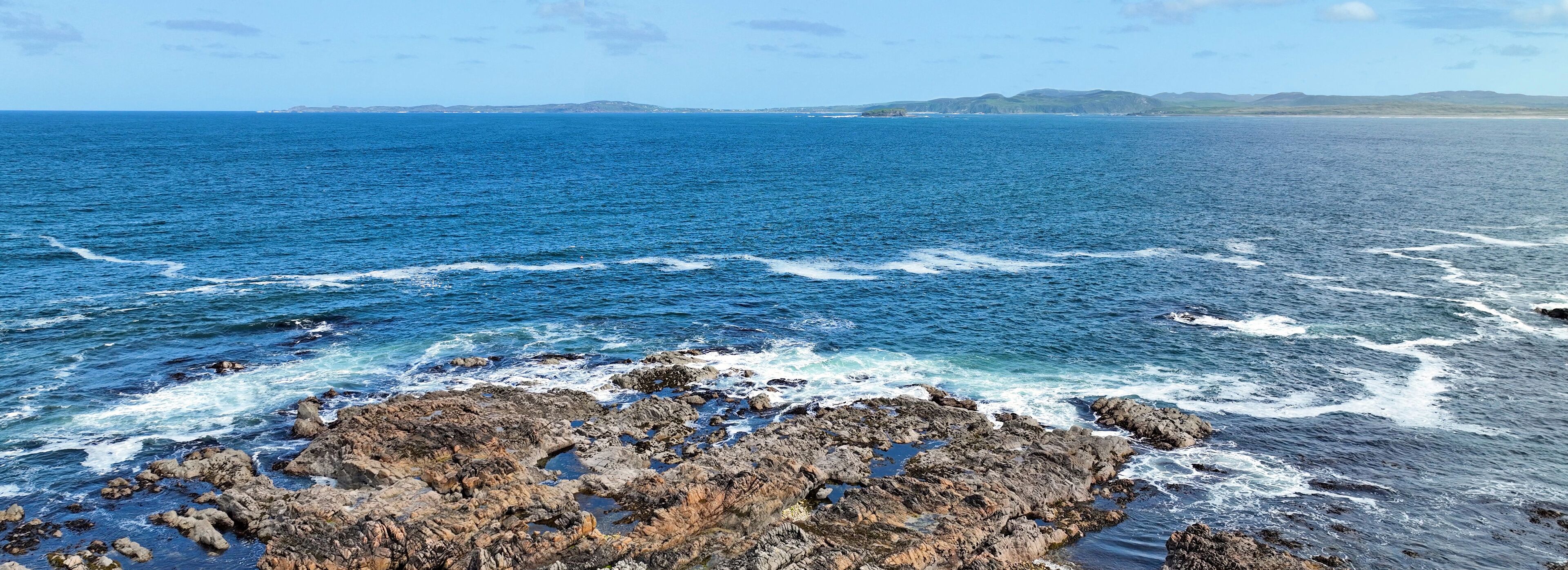 A rocky coastline with waves crashing against the rocks.