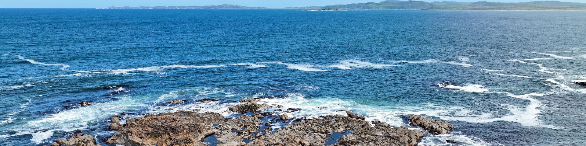 A rocky coastline with waves crashing against the rocks.