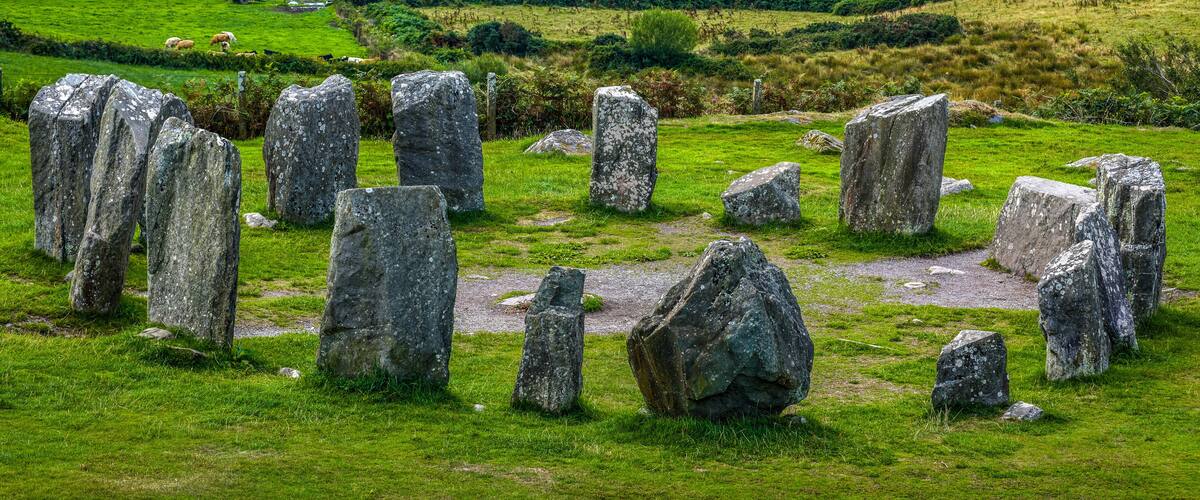A stone circle in a lush green field with rolling hills in the background.