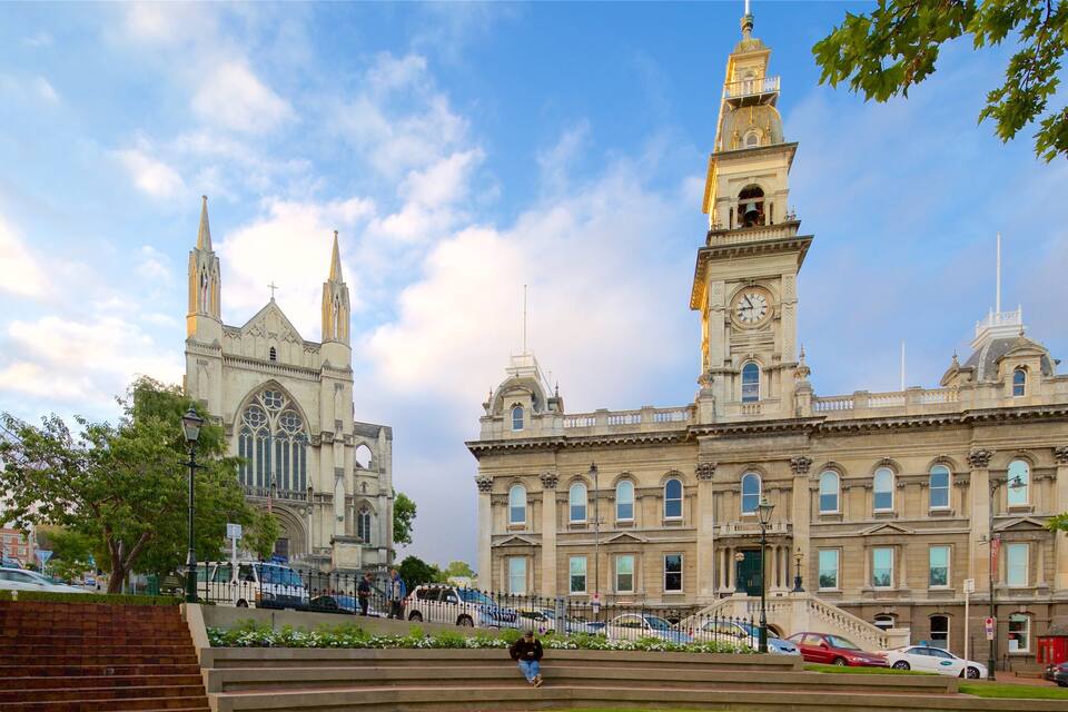 A historic building with a clock tower and a cathedral in the background.