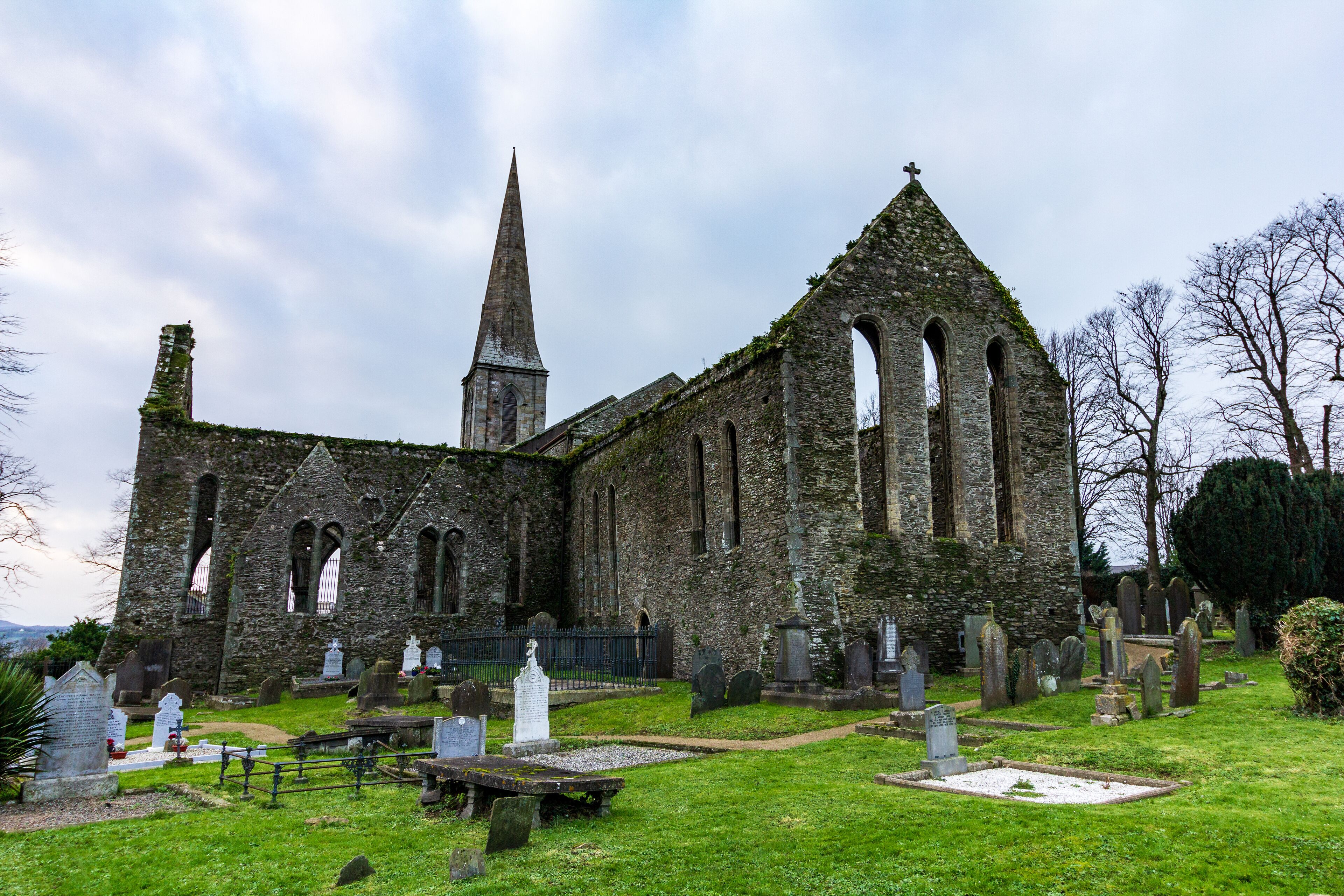 An old church with a tall spire and multiple arched windows.