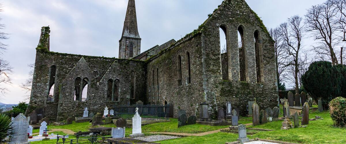An old church with a tall spire and multiple arched windows.