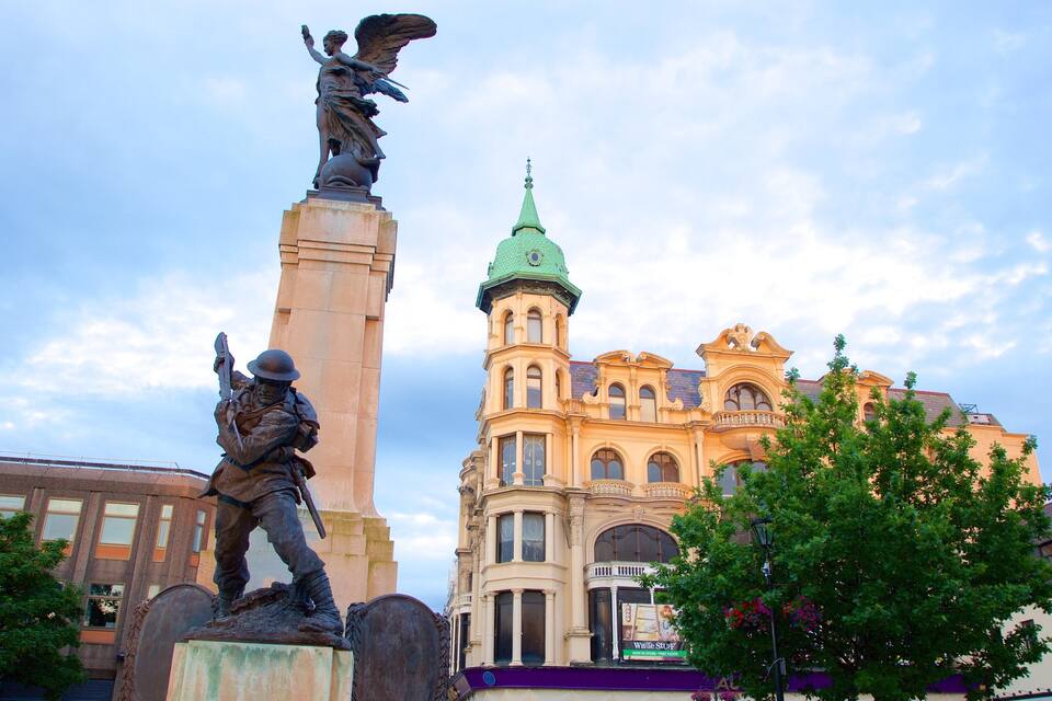 A statue of a soldier holding a rifle, a monument with an angel, and a historic building with a green spire.