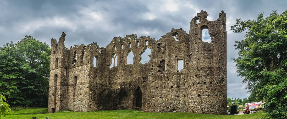 A historic stone castle ruin surrounded by lush greenery.
