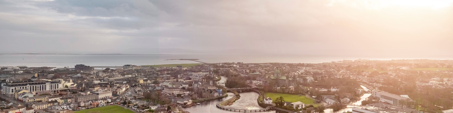 Aerial drone view on Galway city. River Corrib and rowing club. Dark dramatic sunset sky. Nobody. Popular tourist and business city with rich history.