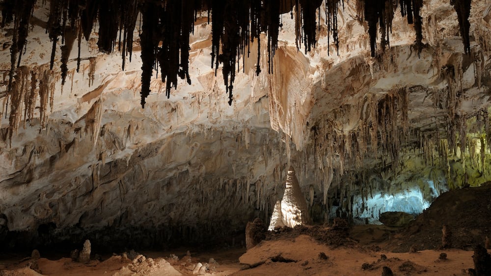 Une grotte ornée de stalactites et dotée d’une colonne centrale.