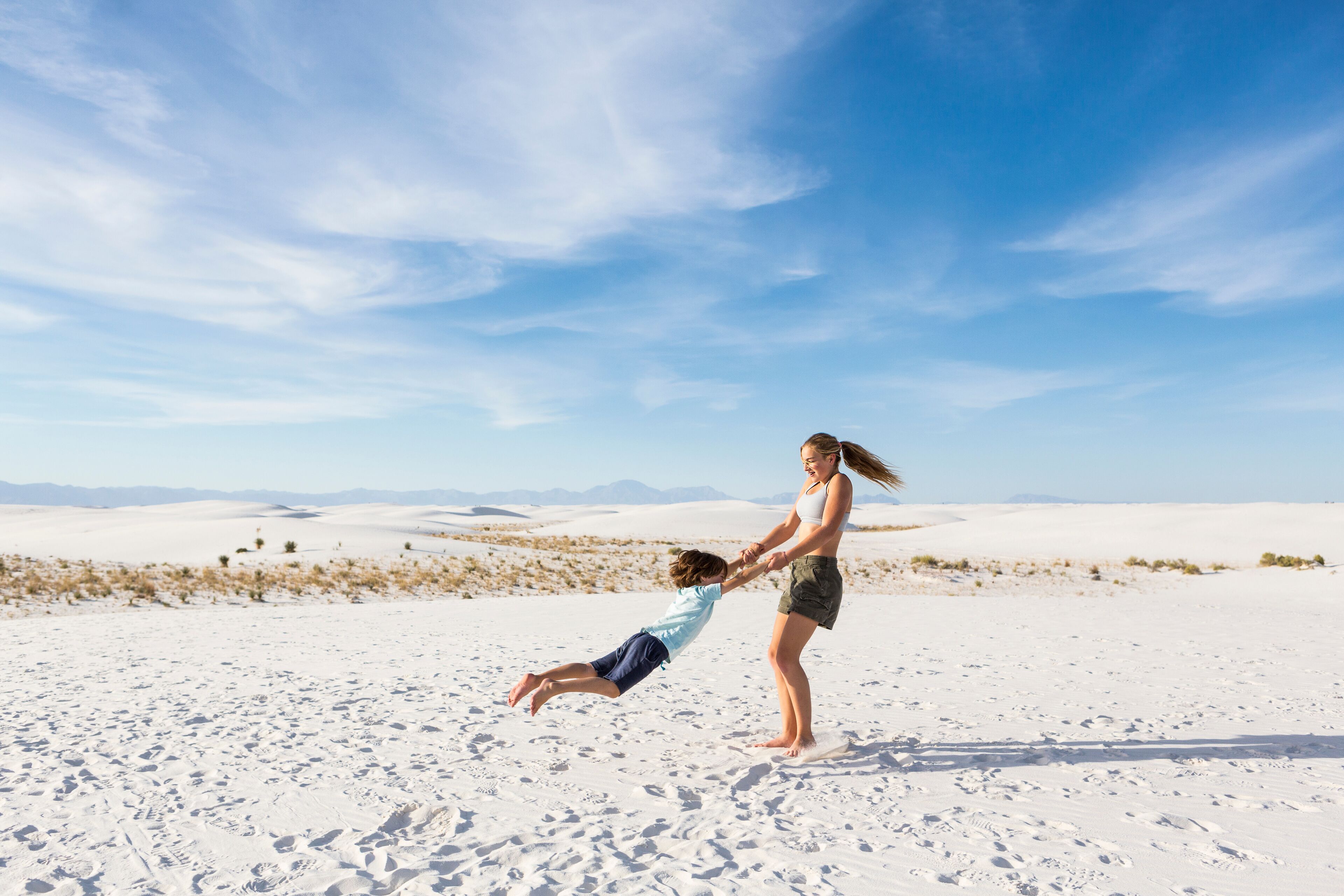 teen girl swinging her 6 year old brother in sand, White Sands Nat'l Monument, NM,White Sands National Monument