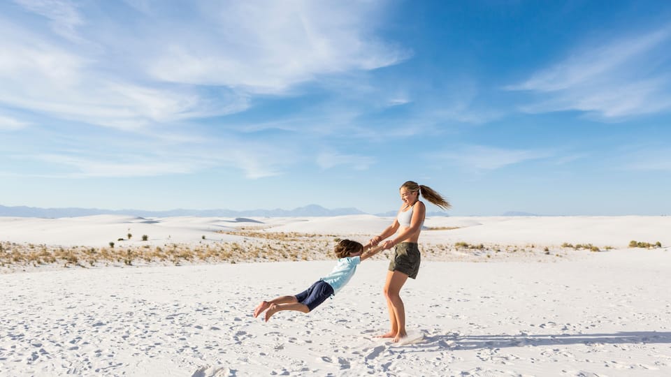 teen girl swinging her 6 year old brother in sand, White Sands Nat'l Monument, NM,White Sands National Monument