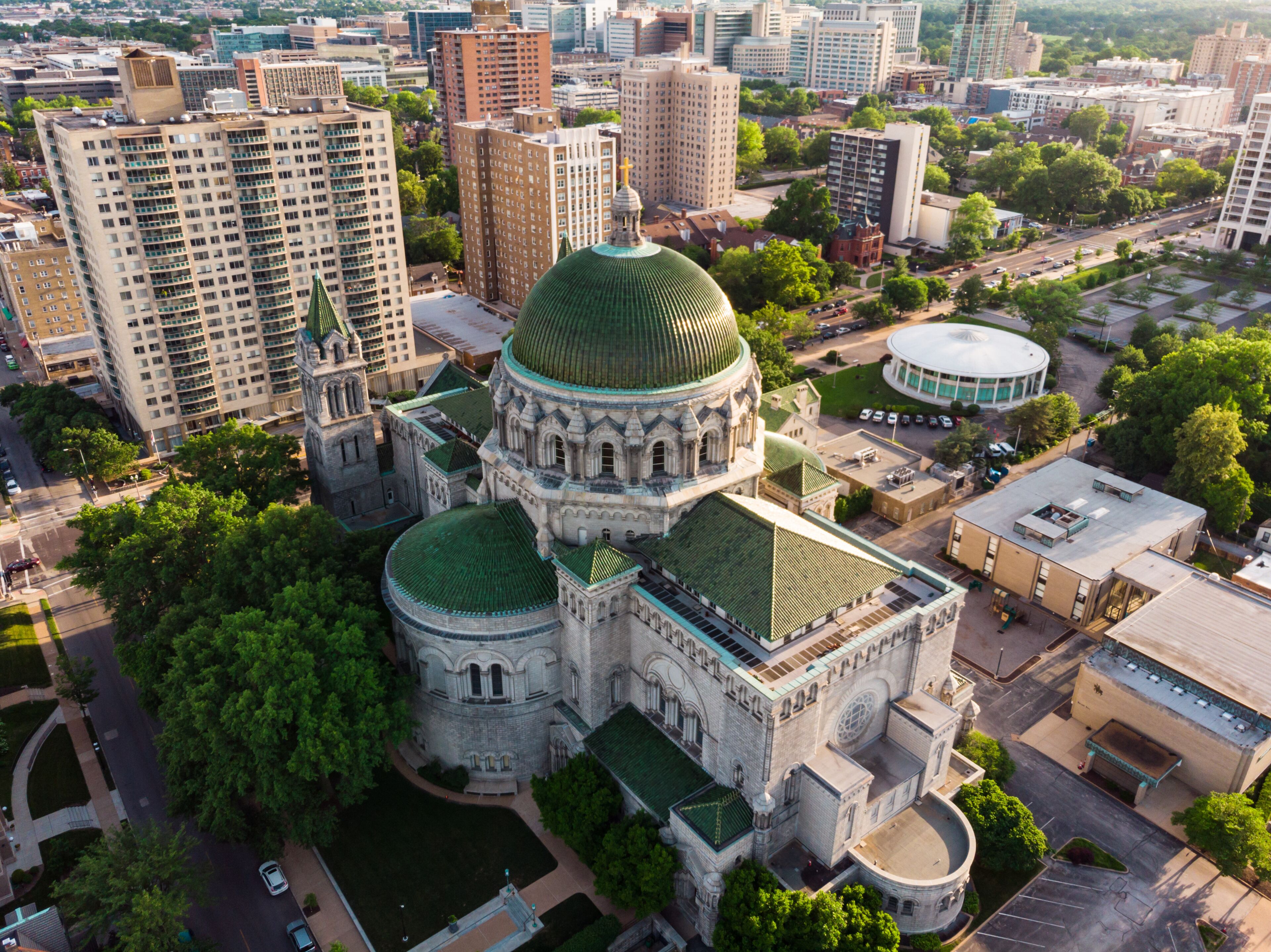 A historic building with a green dome and adjacent modern high-rise buildings.