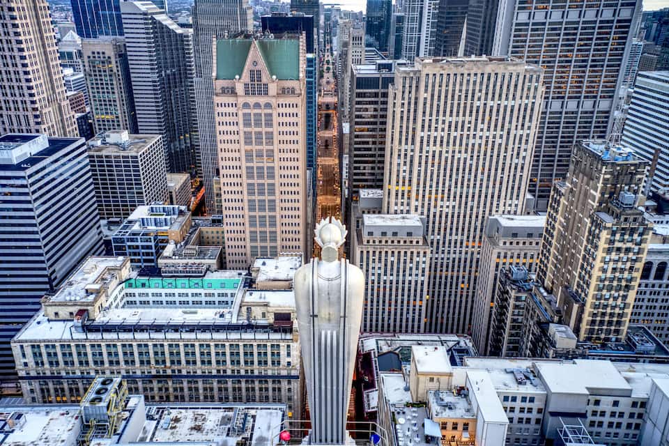Panorama urbano con una statua imponente al centro, circondata da alti edifici.