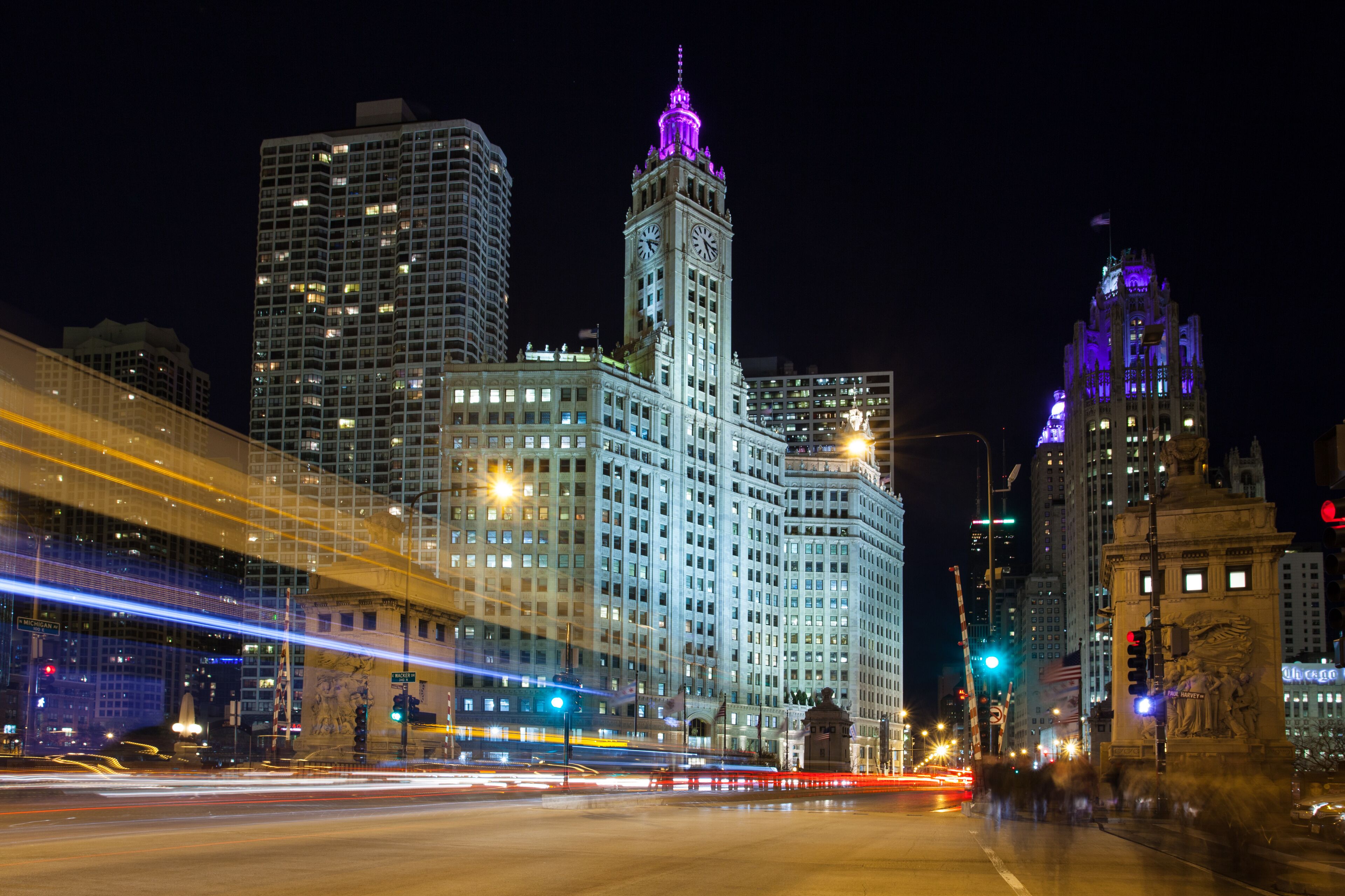 A nighttime cityscape with illuminated skyscrapers and a prominent clock tower.