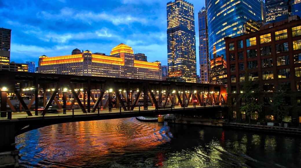 Chicago's illuminated night lights over Chicago River and at Merchandise Mart during rush hour.