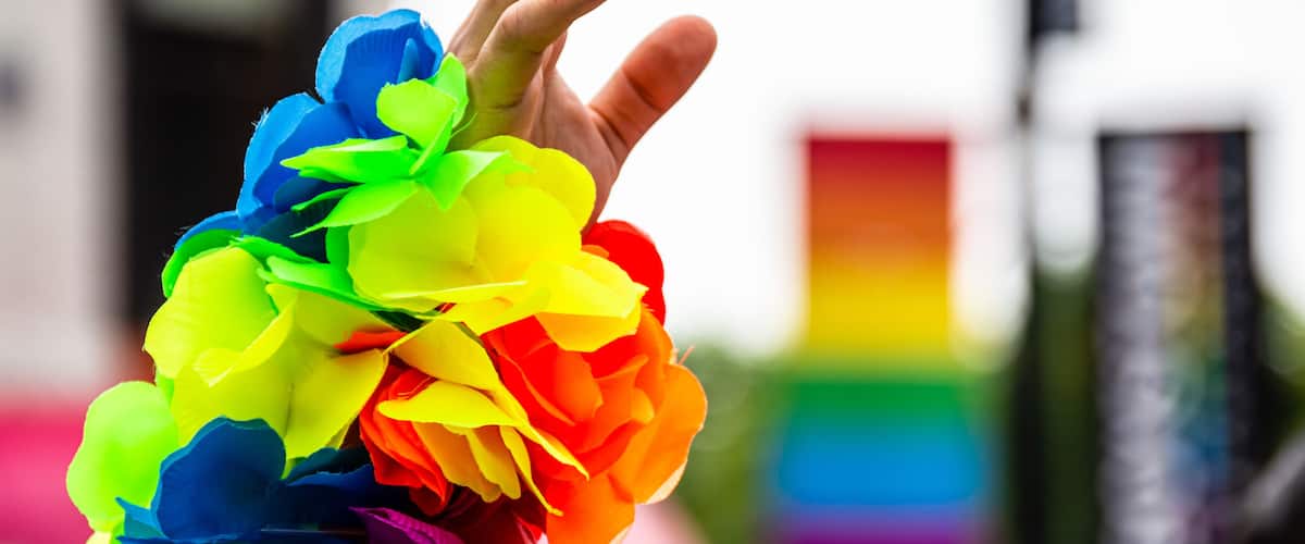 A man's hand is waving in the air and wearing a rainbow bracelet at Gay Pride parade.