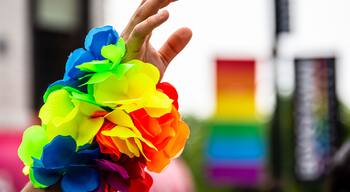 A man's hand is waving in the air and wearing a rainbow bracelet at Gay Pride parade.