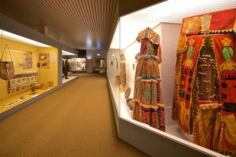 An indoor museum exhibit with traditional textiles and artifacts on display.
