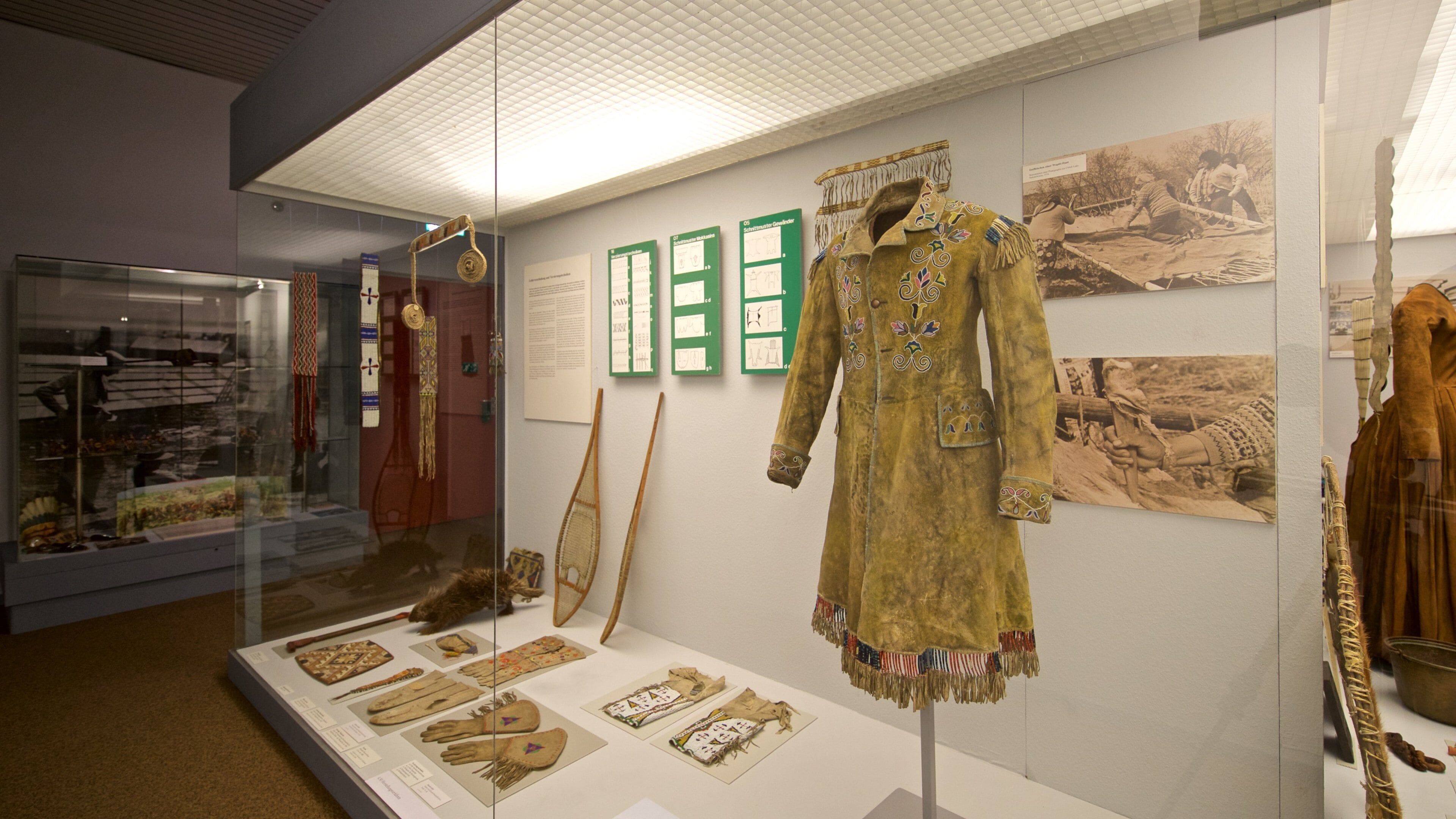 Une exposition de musée présentant des vêtements traditionnels, des objets d’art et des panneaux d’information.