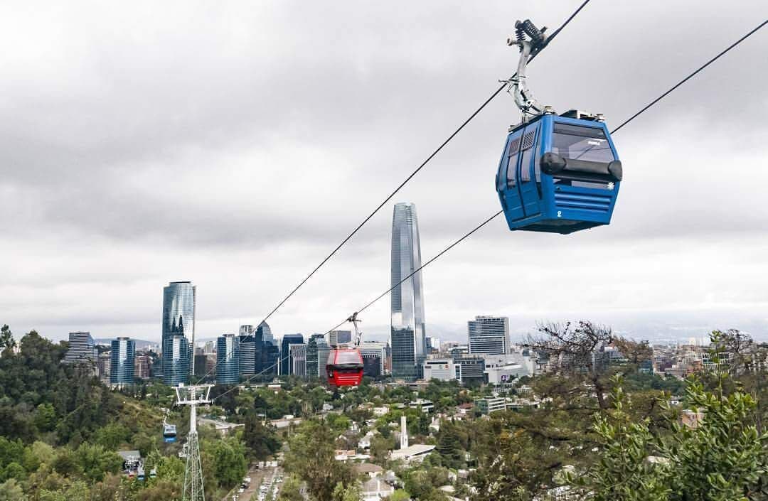 Um sistema de teleférico com o skyline da cidade ao fundo.