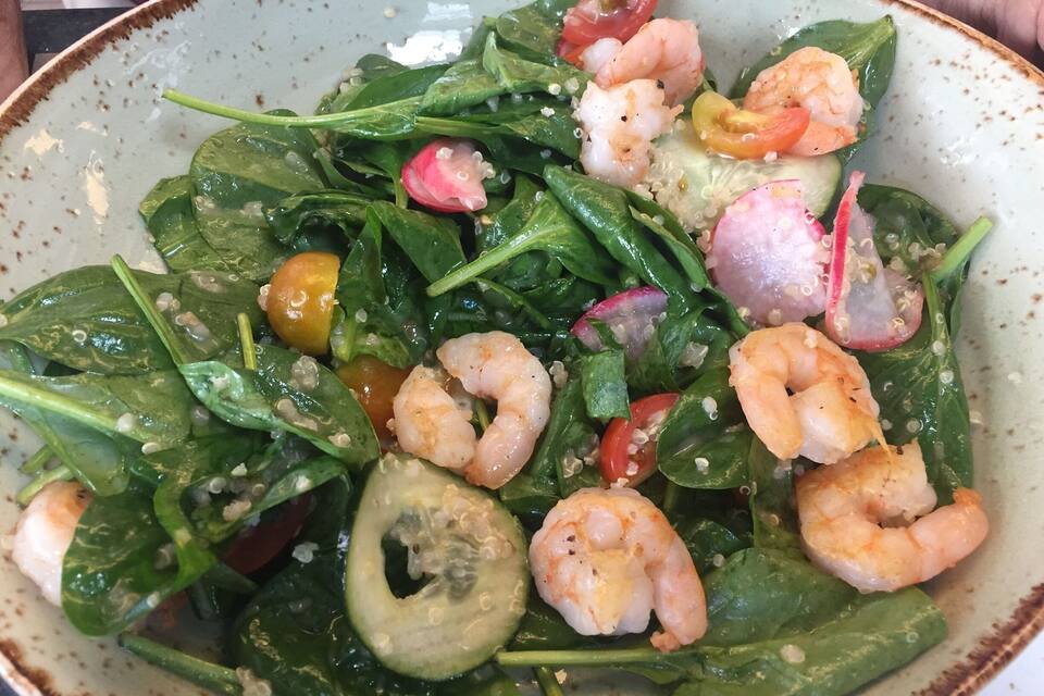 A bowl of salad with spinach, shrimp, radishes, and cherry tomatoes.
