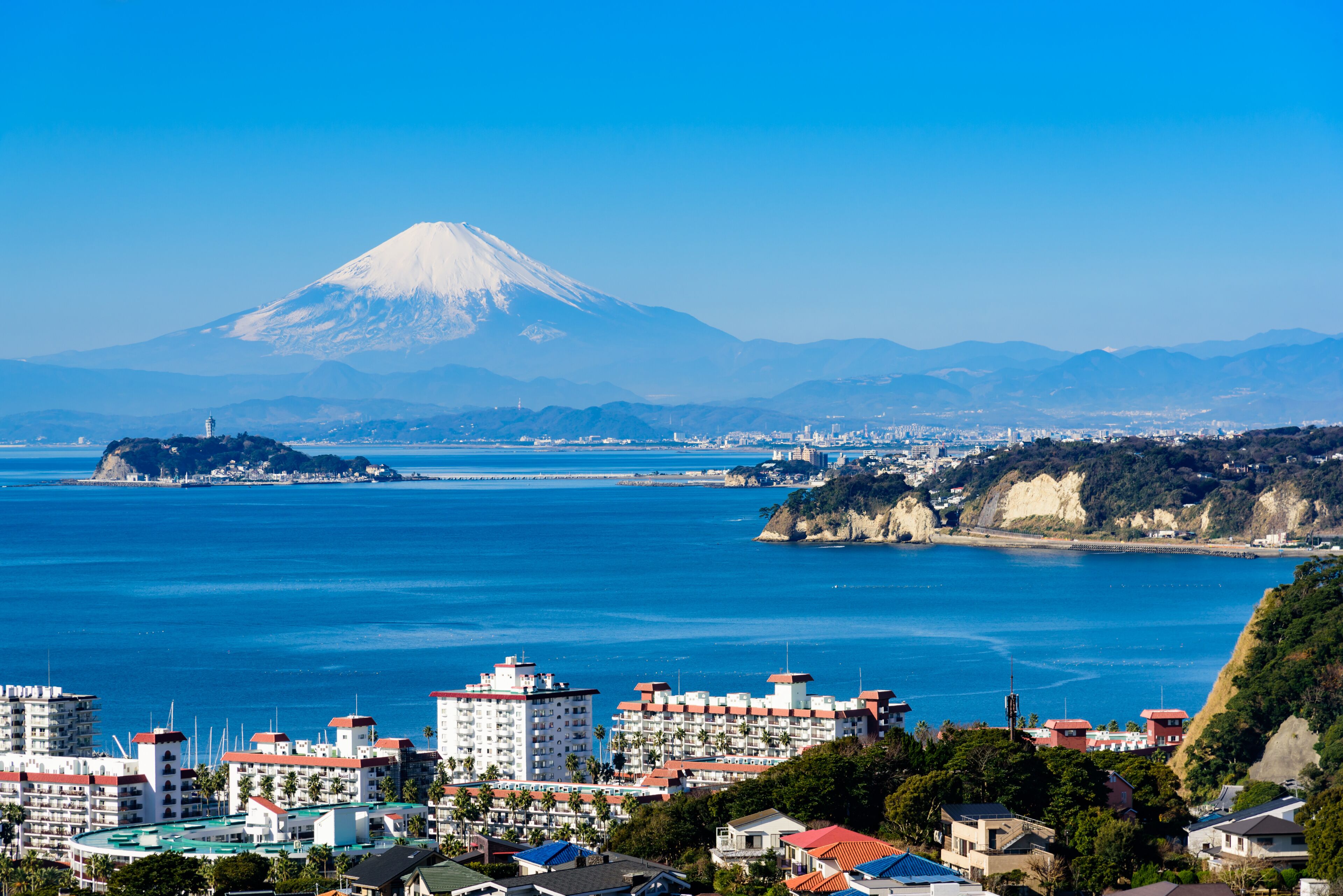 A coastal cityscape with a prominent mountain in the background.