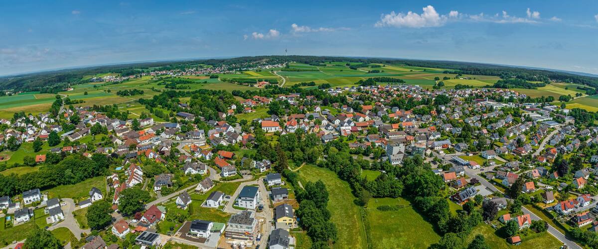An aerial view of a town surrounded by green fields and a distant tower.