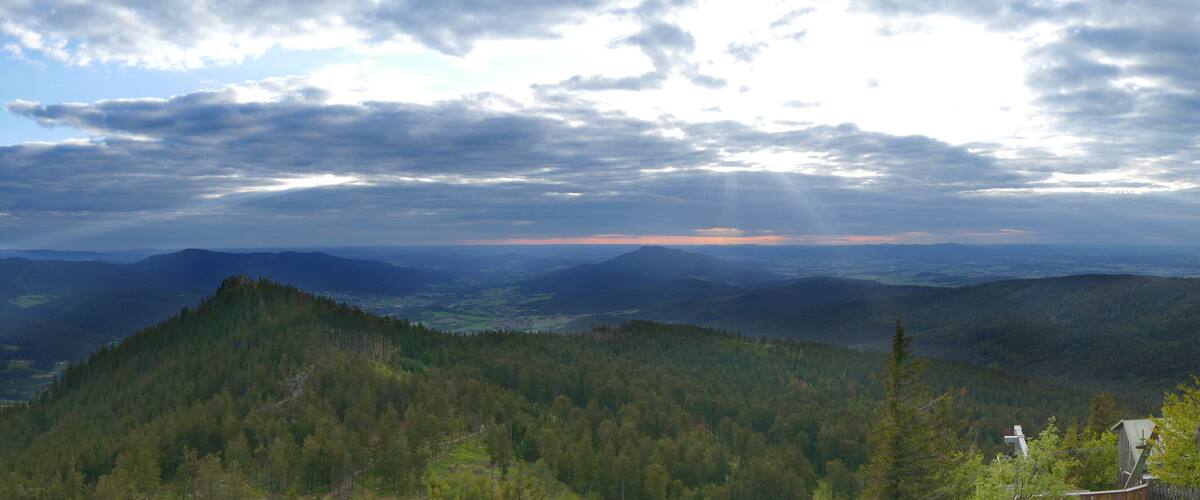A mountainous landscape with dense forests and a distant view of a town.