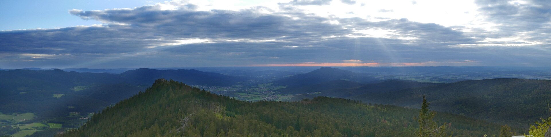 A mountainous landscape with dense forests and a distant view of a town.