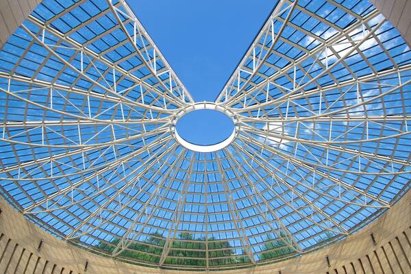 A large, circular glass roof structure with a central opening, supported by a metal framework.