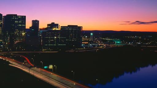A city skyline at dusk with illuminated buildings and a prominent tower.