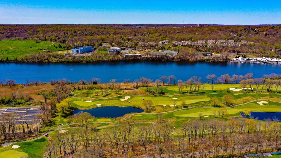 A golf course with a lake, residential area, and industrial buildings.