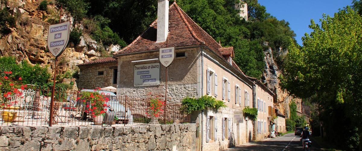 A stone building with a tiled roof and signs advertising local products and services.