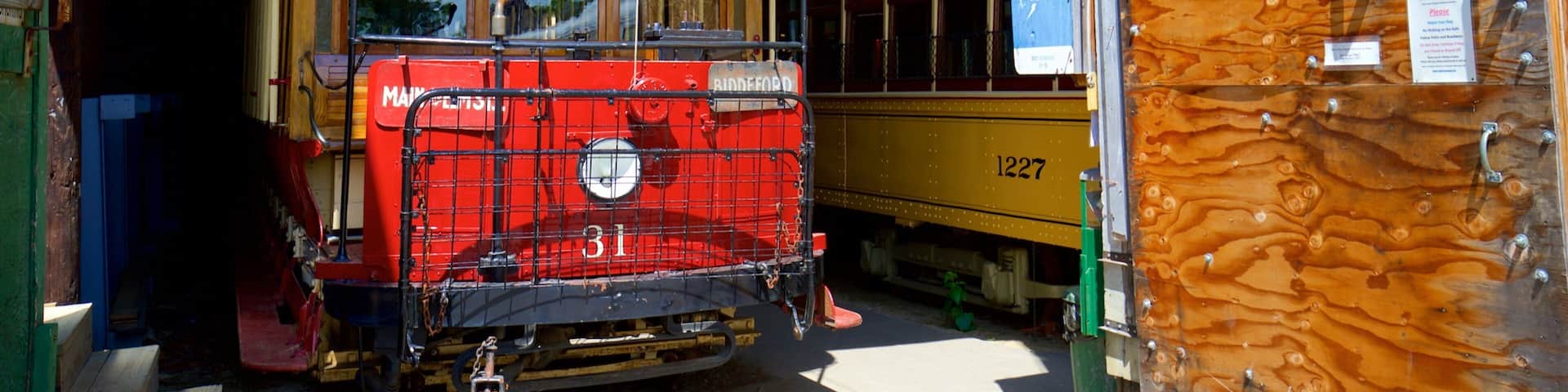 Un chariot rouge sur lequel on peut lire le mot « BIDDEFORD », garé à l’intérieur d’un bâtiment aux murs en bois, avec une pancarte indiquant « SORTIE ».